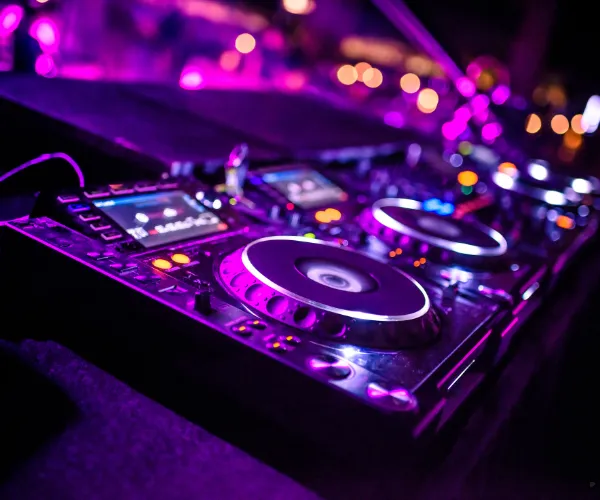 A DJ controller lit in magenta and violet.