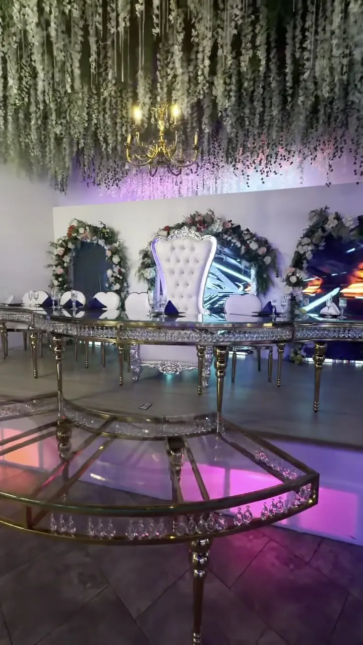 Una mesa principal enmarcada por flores y un candelabro sobre una plataforma de espejo.