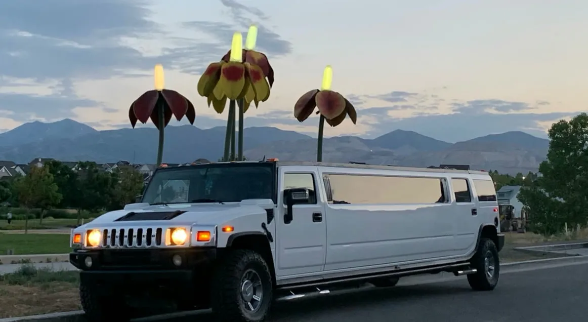 The white stretch Hummer limousine parked at dusk with the Wasatch mountains behind it.