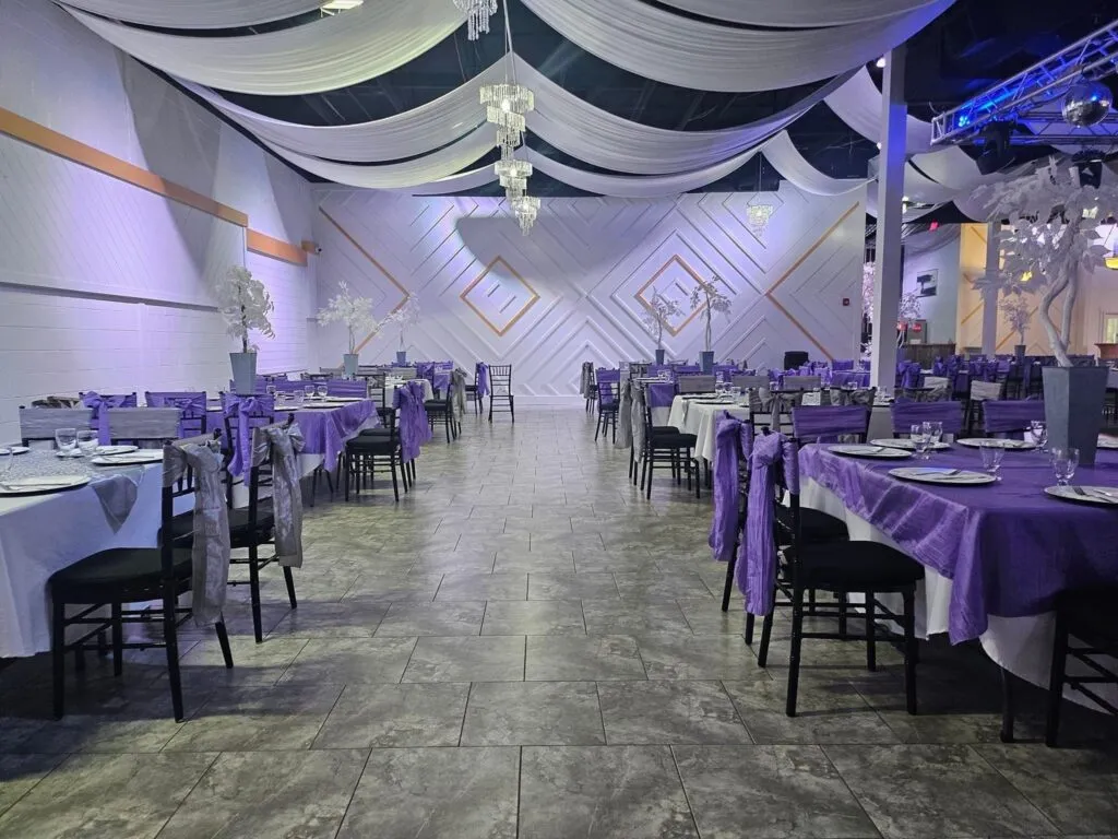 The hall arranged for a reception with purple linens and geometric wall detailing.